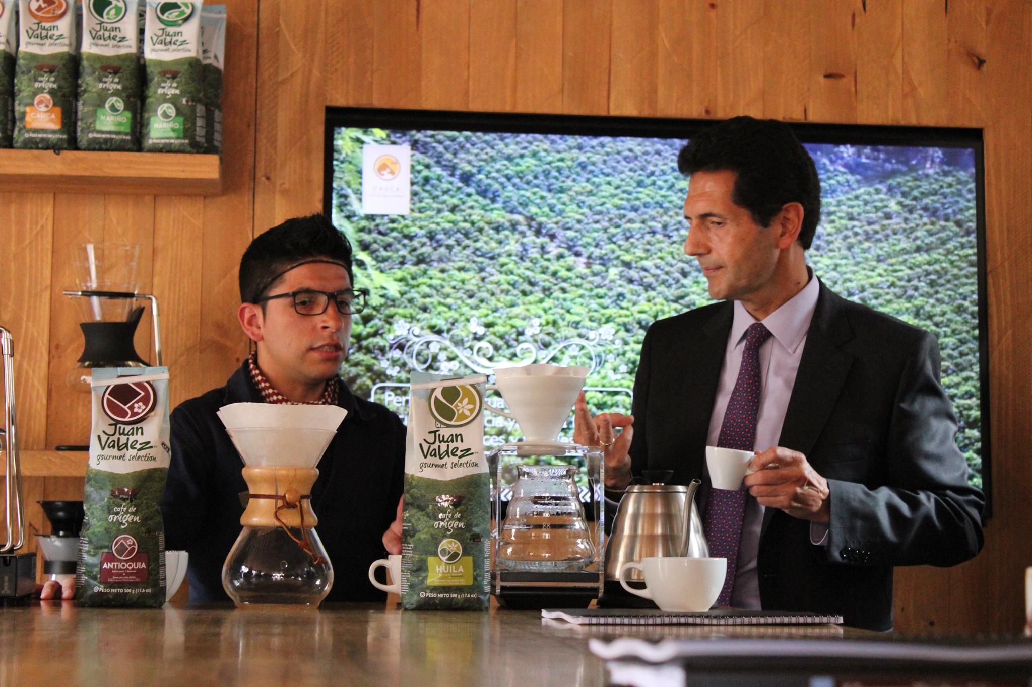 Procafecol President Hernan Mendez with Baricultore in Mug of Coffee at Juan Valdez Cafe in Bogota, Colombia