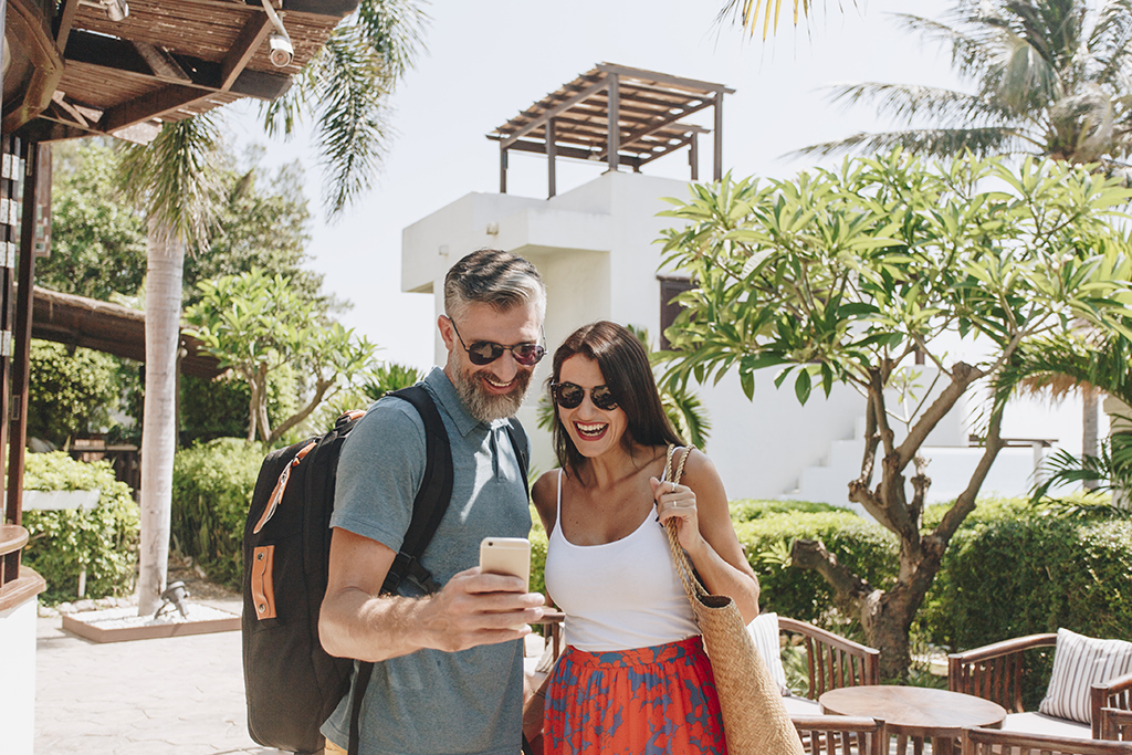 Couple Using Mobile Travel App on Cell Phone