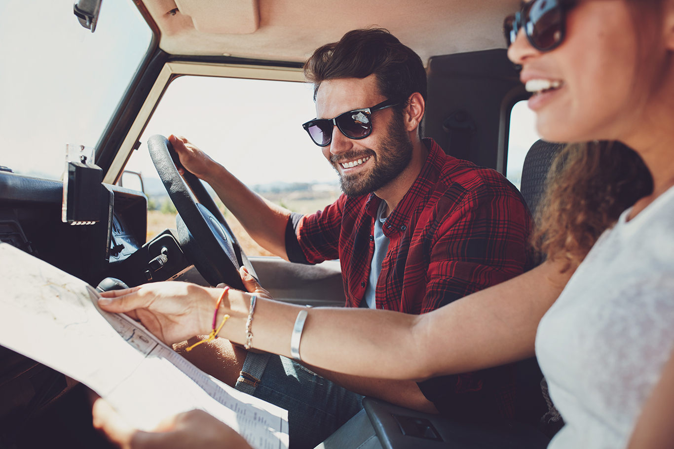 Couple Planning Road Trip with Map in Rental Car