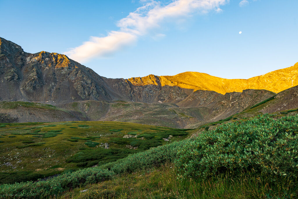 Sunrise alpenglow over a lush green valley on the Grays Peak Trail in Colorado