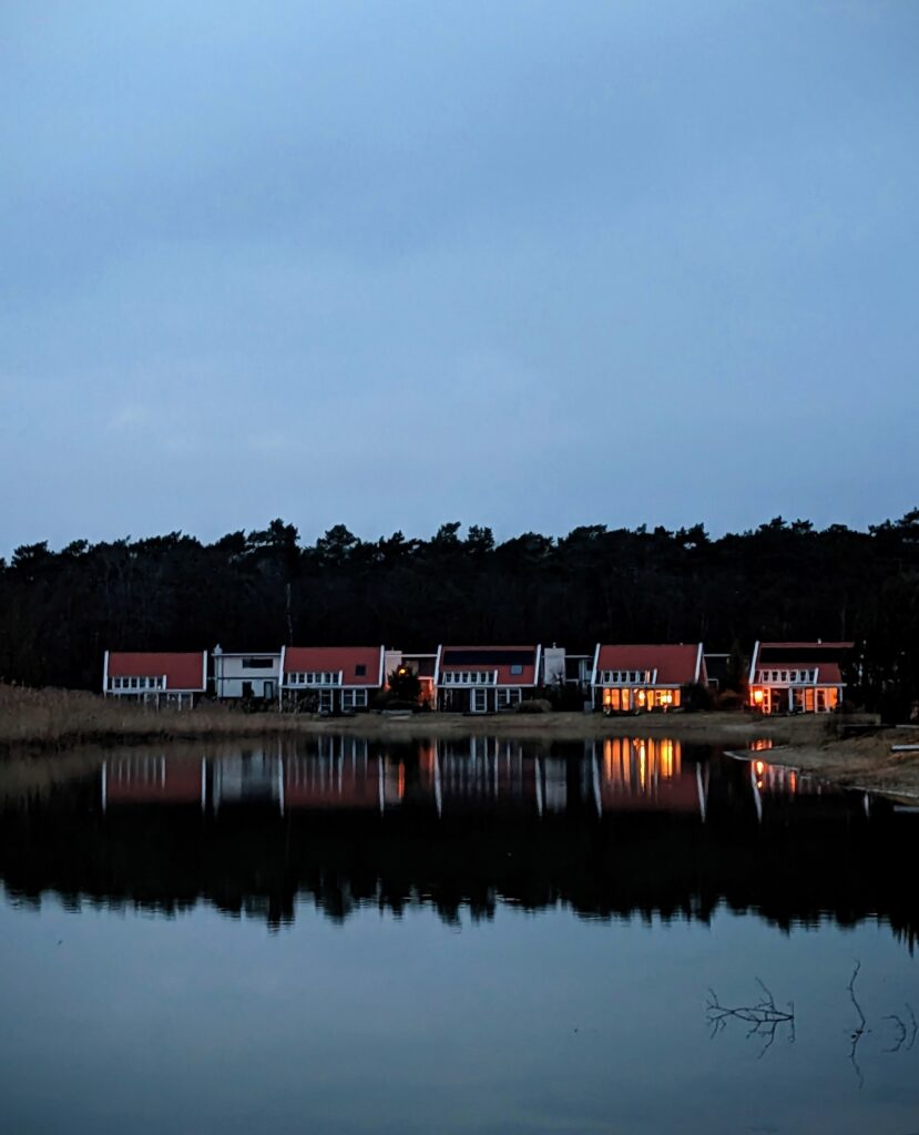 Cottages Aglow Reflecting on a Pond at EuroParcs de Zandig in Otterlo, The Netherlands