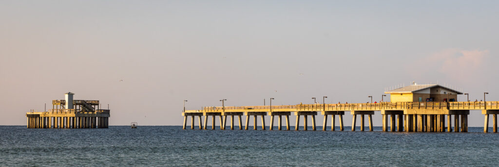 A fishing boat passes between the gap in Gulf State Park Pier, which was damaged by Hurricane Sally