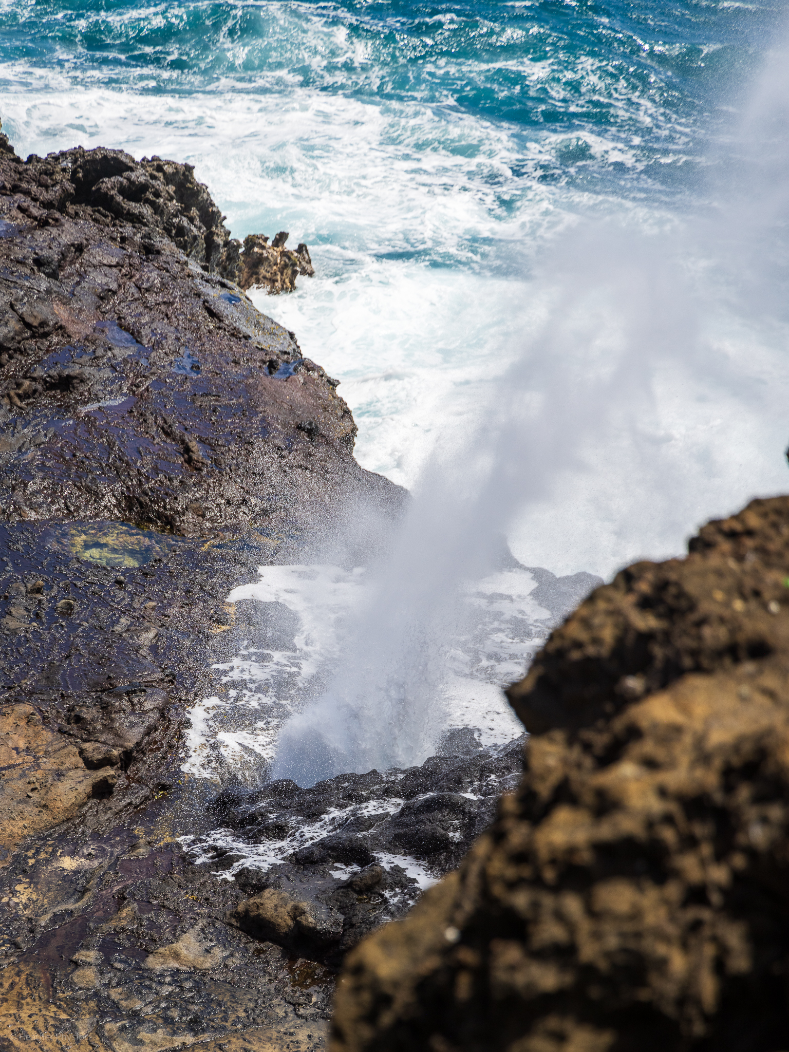 The Halona Blow Hole lava tube briefly spews ocean spray