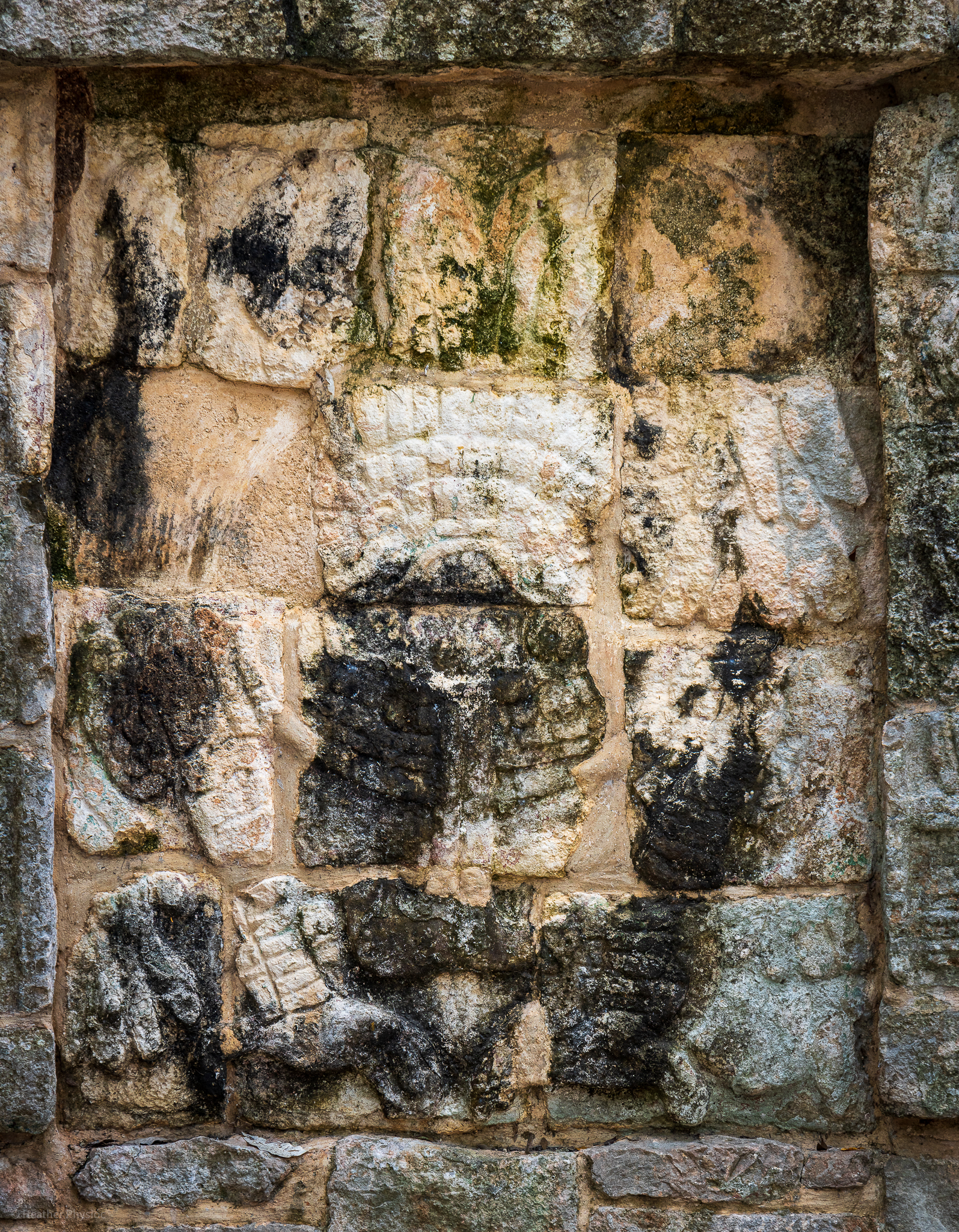 A close-up of the eroded ancient Mayan relief carvings on a stone wall at Chichen Itza. The image captures the textural details and the remnants of etchings despite the wear over centuries.